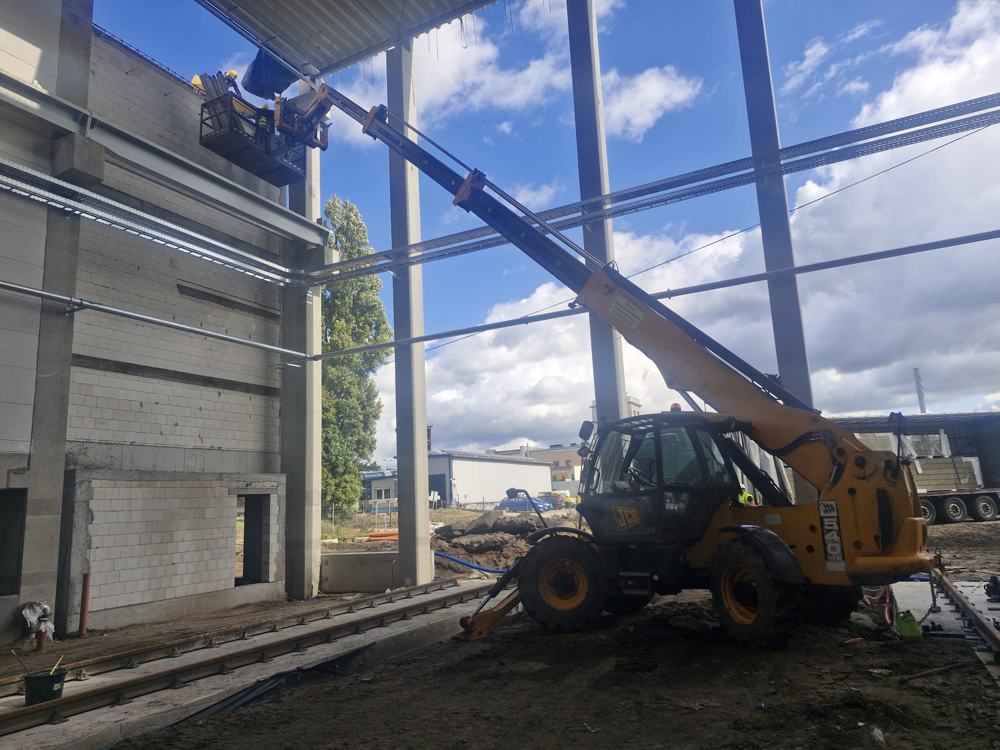 Operator ładowarki teleskopowej przy montażu elementów elewacji